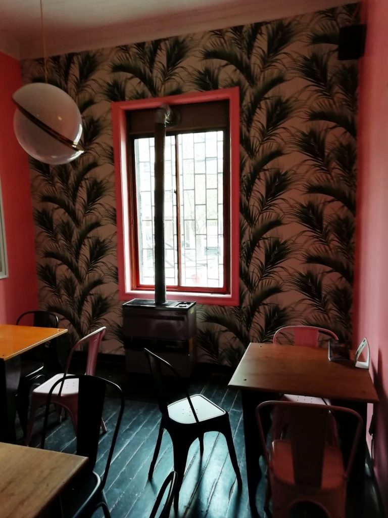 Instalación Papel mural decorativo paredes de color rosa y papel tapiz con estampado de hojas de palma.