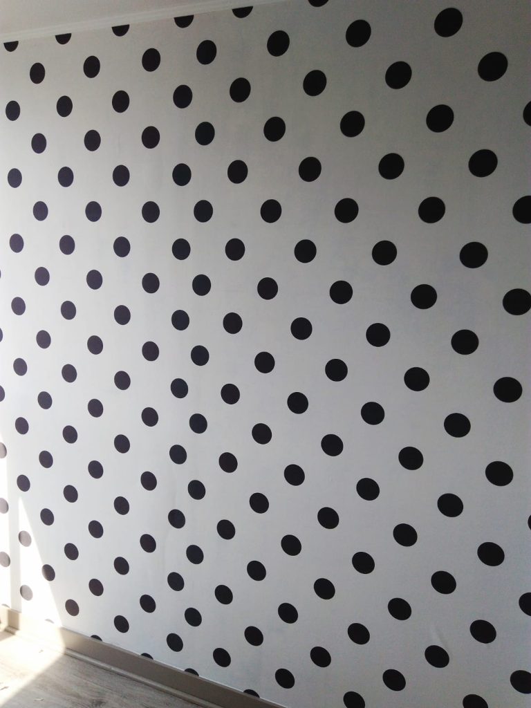 Instalación Papel Mural Decorativo de lunares negros sobre fondo blanco. Los lunares están dispuestos en un patrón diagonal